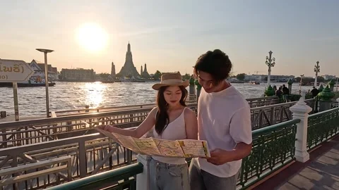 Young Couple Reading City Map by Riverside at Sunset Stock Footage 325273873