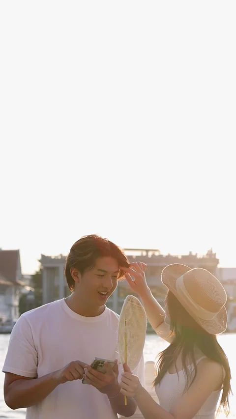 Young Couple Reading Map by Riverside Temple at Sunset Stock Footage 323155624