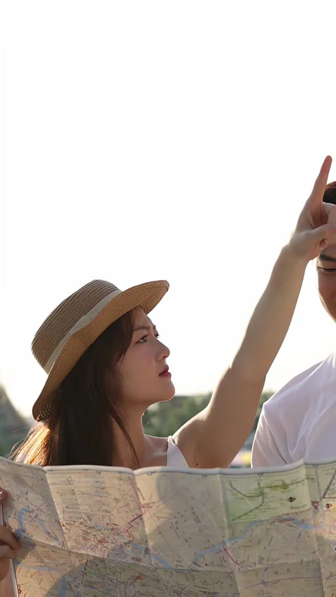 Young Couple Reading Map by Riverside Temple at Sunset Stock Footage 323352221