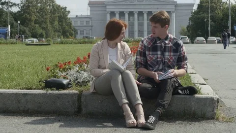 Young couple reading in park Видео 77846533