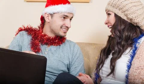 Young Couple with Red Santa Hat, Sitting on Couch Stock Photos