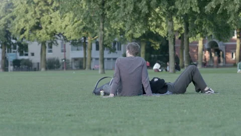 Young Couple Relaxing and Talking on Green Grass in City Park Stock Footage 343982782