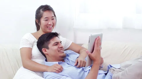 Young Couple Relaxing on Couch with Tablet Computer Stock Footage 27255424