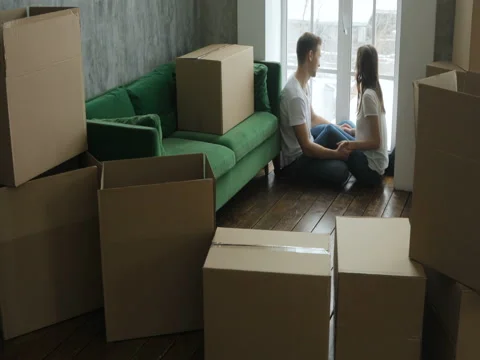 Young couple relaxing laughing after unpacking cartons from house move Stock Footage 84654053