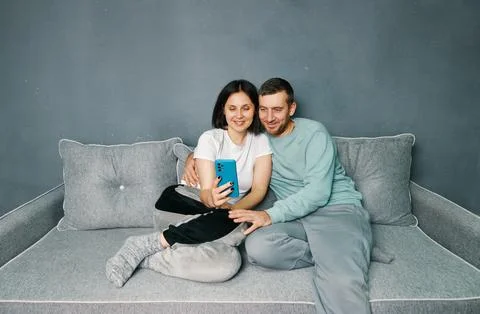 Young couple relaxing on sofa using mobile smart phone relaxing at home Stock Photos