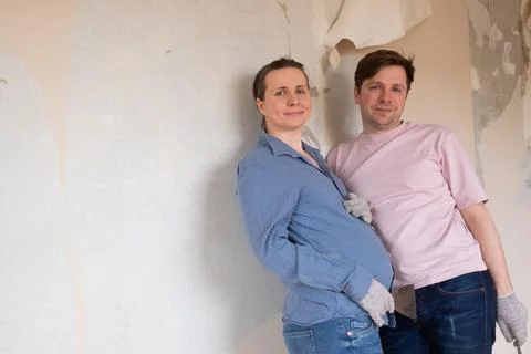 Young couple removing old wallpaper from walls preparing for flat renovation. Stock Photos