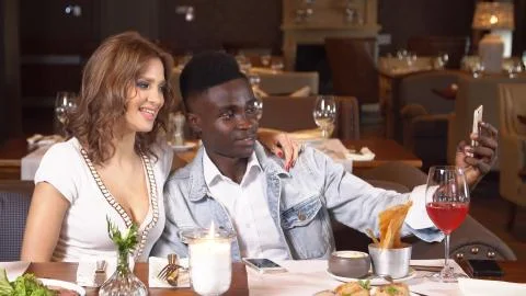 Young couple in restaurant using smartphone. Stock Photos