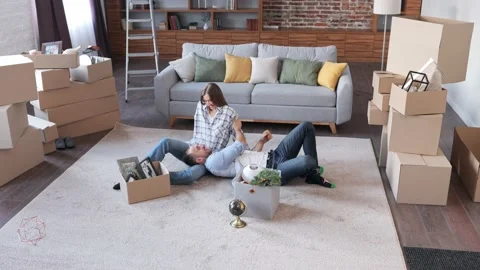 Young couple resting on carpet between cardboard boxes and discussing interior Stock Footage 213313663