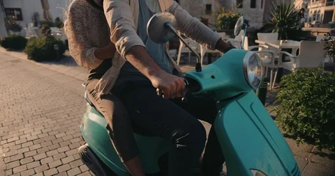 Young couple riding retro motorcycle on cobblestone European city street Stock Footage