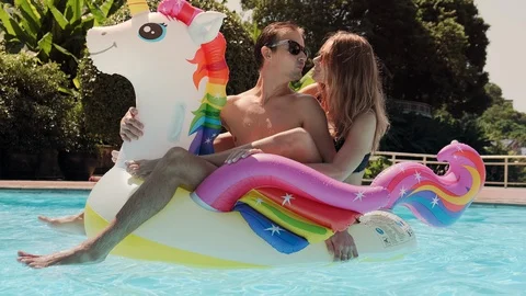 A young couple riding a unicorn in the pool enjoys freedom and vacation Stock Footage 128024496