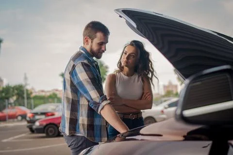 Young couple on the road having problem with a car. Open hood of broken car. Car Foto stock