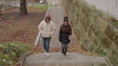 A young couple on a romantic date walking up stairs in an autumn city park. 스톡 동영상 311462416