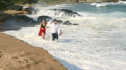 Young couple running along the beach shoreline Stock Footage 62216476