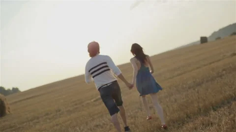 Young couple running through the wheat field at sunset Stock Footage 54637488