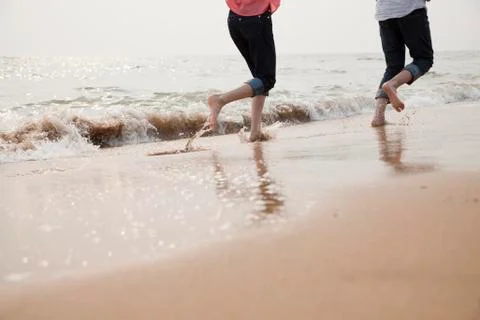 Young Couple Running in the Waves Stock Photos