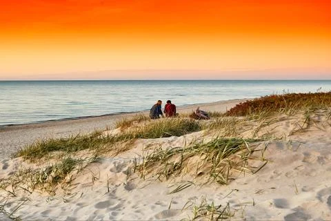 Young couple on a sea beach at summer sunset. Romantic landscape. Stock Photos