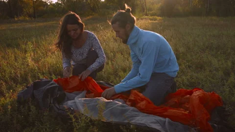 Young couple sets up a tent in a mountain forest at sunset. Stock-Footage 116953812