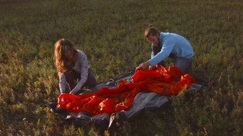 Young couple sets up a tent in a mountain forest at sunset. Video stock 116953900