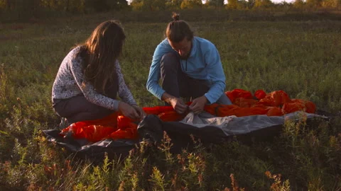 Young couple sets up a tent in a mountain forest at sunset. Stock Footage 116953901