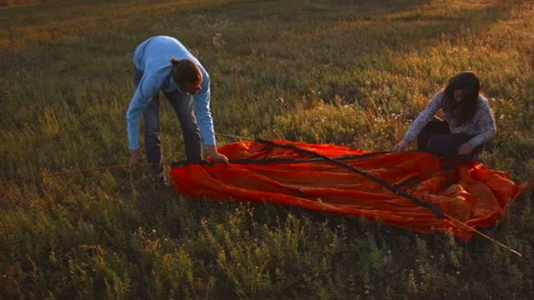 Young couple sets up a tent in a mountain forest at sunset. Vídeo Stock 116955393