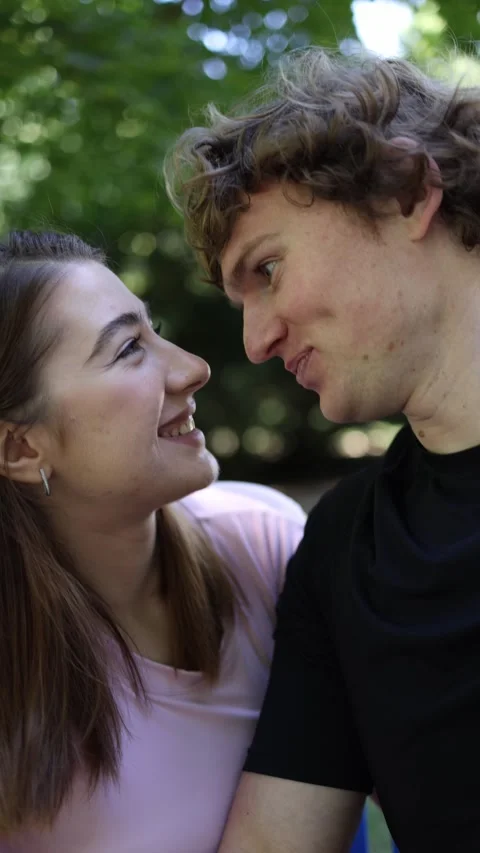 Young couple share romantic eye contact while falling in love in a park Видео 341476801