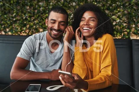 Young couple sharing earphone for listening music on mobile phon Stock Photos