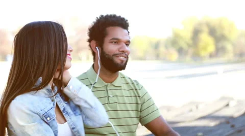 Young couple sharing earphones while listening to music Stock Footage 59555071