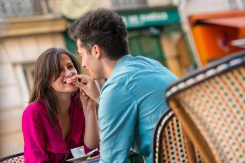 Young couple sharing macaron at pavement cafe, Paris, France Foto stock
