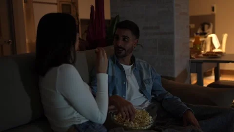Young couple sharing popcorn while watching movie on sofa Stock Footage 302927953