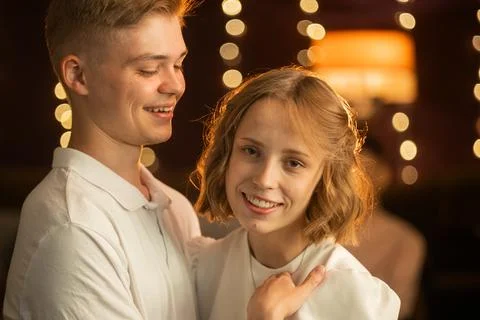 Young couple sharing a tender moment with warm bokeh lights in the background Stock Photos