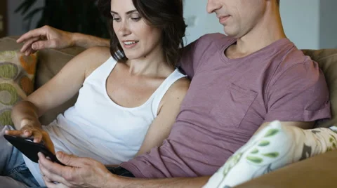 Young couple shopping on internet with tablet, sitting on a couch, side view Stock Footage 65991478