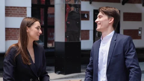 A young couple sit on a bench and chat, high-five each other Stock Footage 129638527