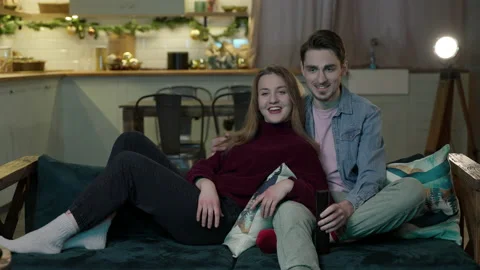 A young couple sit hugging on the couch watching a movie Stock Footage 167555392