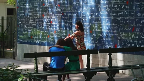 Young Couple sit at the romantic wall of love art attraction, Montmartre Stock Footage 308205544