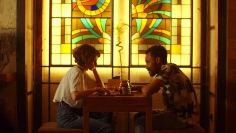 Young couple sit at a table in a cafe and talk, man pour tea in cups Stock Footage 121934476