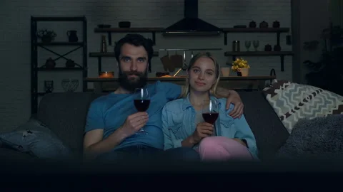 Young couple siting on the sofa, hugging, drinking wine and watching TV. Stock Footage 108860191