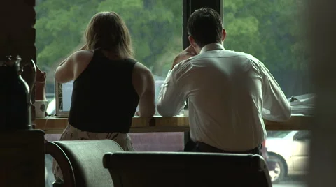 Young Couple Sits in Cafe Looking out Window Stock Footage 61322937