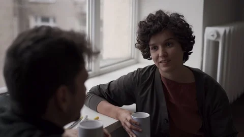 A young couple sits talking and chatting at a large window next to a Christmas Video stock 118537637