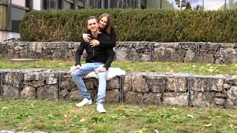 A young couple sits on a white bedspread in autumn park Vidéo 96542163