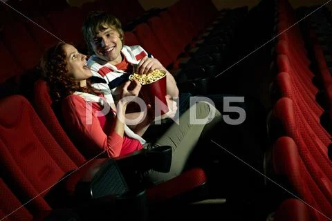 Young couple sitting alone at cinema hall Stock Photos