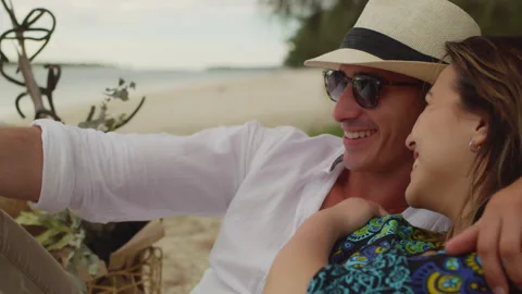 Young couple sitting and looking out at the ocean on the beach in Australia with Stock Footage 199460688