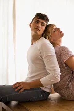 A young couple sitting back to back on a table Stock Photos