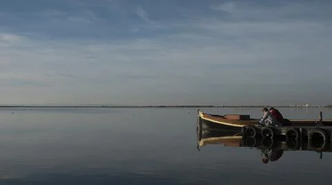 Young couple sitting back to back on the wooden pier in the Albufera of Valencia Stock Photos