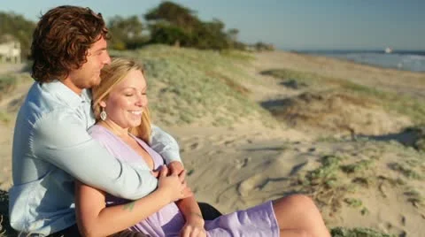 Young Couple Sitting on Beach Medium View Stock Footage 21833301
