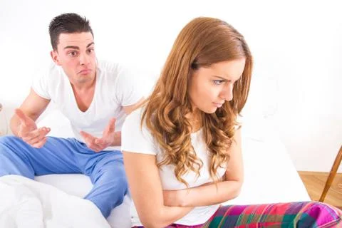 Young couple sitting on the bed because of relationship difficulties. Stock Photos