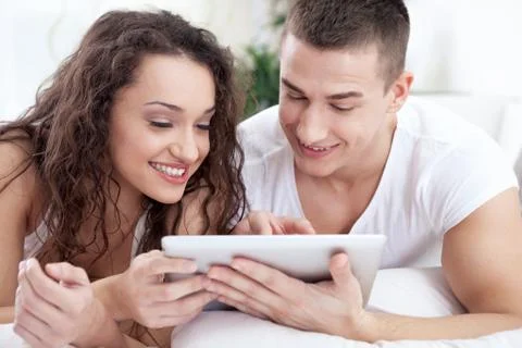 Young couple sitting on the bed using tablet pc Stock Photos