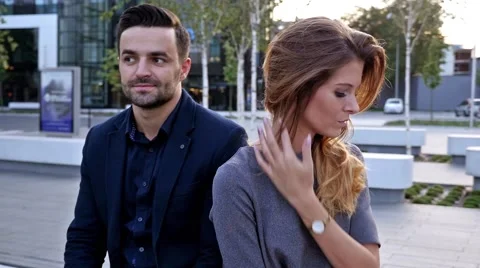 Young couple  sitting on a bench back to back. Outdoor photo Stock Footage 56303616