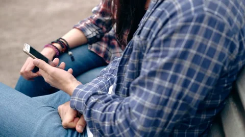 Young couple sitting on bench in the city and watching on smartphone Stock Footage 63175437