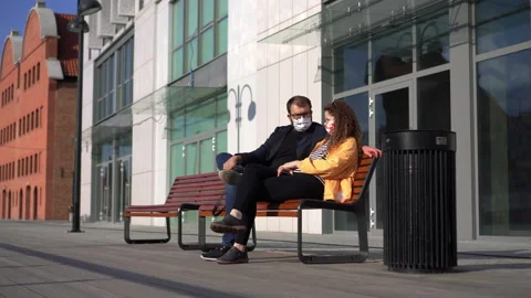 Young Couple Sitting on a Bench, Faces Covered with Protective Masks Stock Footage 132503007