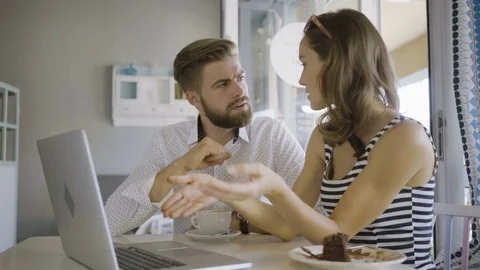 Young couple sitting in a cafe and looking at laptop discussing vacation plan Video stock 79794344